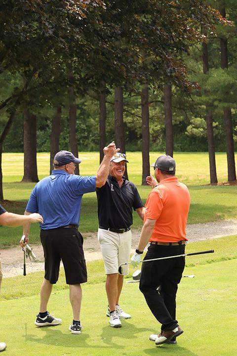 Team members from sponsor Young Industries Inc. – Steve Kelchner (in blue) and Tyler Thompson – congratulate Funk on a hole-in-one.