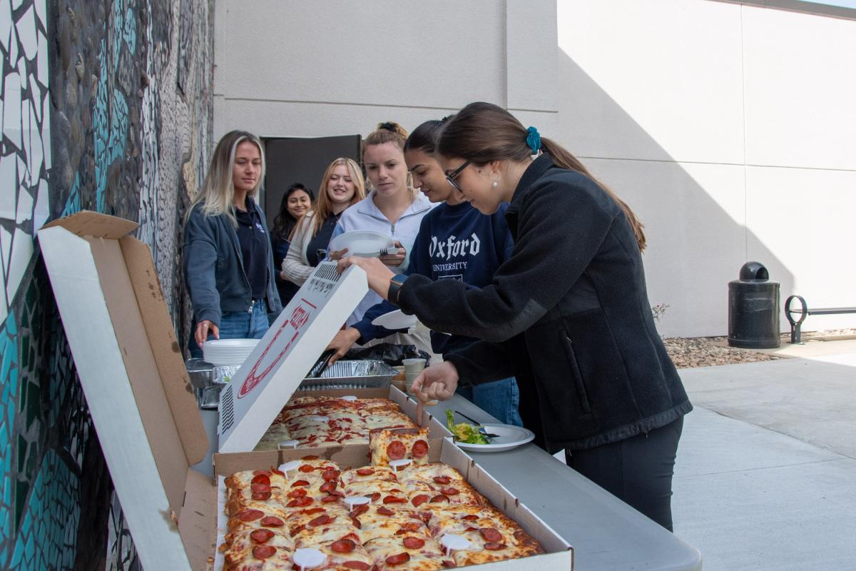 Students take a break in their final day of study before Fall Break to partake in pizza and conversation outside the Physician Assistant Center.