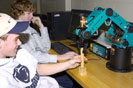 Visiting students program a robotic arm to move wooden blocks