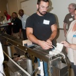 A participant pulls processed plastic material from the twin-screw extruder