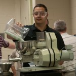 A participant adds material to the hopper during a session on twin-screw compounding