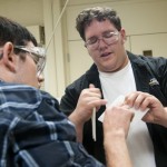 Ryan L. Newman, right, a recent plastics and polymer engineering technology graduate and a research assistant for the Plastics Innovation and Resource Center, shows the result of an impact test on a piece of rotationally molded plastic.
