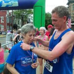 In an emotional tribute to her late husband, Pam Schuman accepts Denny Dunkleberger's race medal.