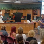 Cody J. Miller, line cook at Le Jeune Chef Restaurant (and May graduate in culinary arts technology) and Fred Becker, dean of hospitality, serve up stir-fry along with appetizing facts about working in "the happiness business."