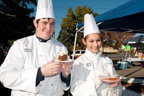 Zachary D. Derck and Hannah E. Marquis, culinary arts and systems students, serve free pumpkin spice cake and warm apple cider to shoppers at the Williamsport Growers' Market.
