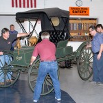 Students and museum personnel maneuver the latest historical "figure" on loan to automotive restoration technology majors.