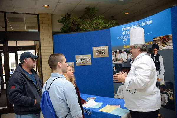 Chef Paul E. Mach, assistant professor of hospitality management/culinary arts, with a family outside Le Jeune Chef Restaurant.