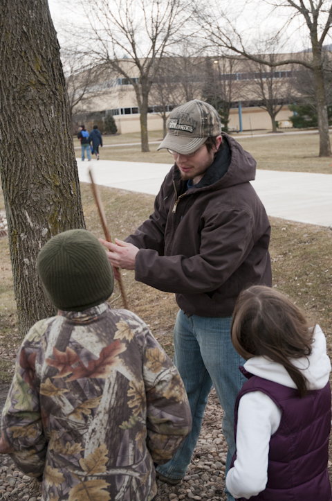 Forest technology student Fisher T. Stewart shows participants how foresters use a measuring tool to estimate the number of 16-foot logs a tree holds.