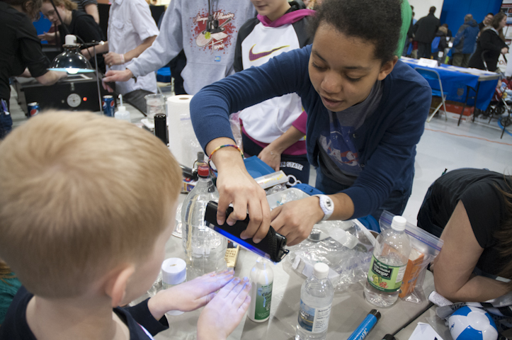A high school student helps a youngster check the cleanliness of his hands.