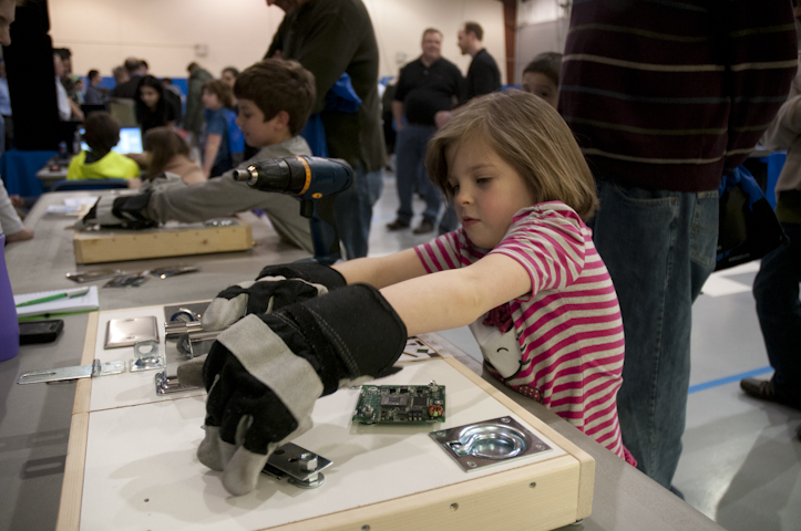 At a NASA Aerospace Education Services booth, a child pretends to make repairs to the space station.