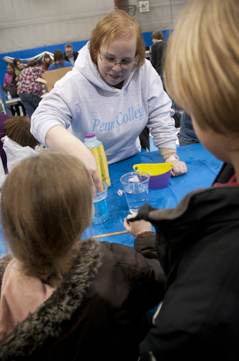 Early childhood education student Amanda A. Galer shows how the surface tension of water changes with the addition of a “super-secret solution” (dish soap).