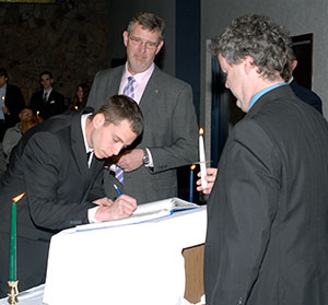 Cody J. Wood signs the membership register, overseen by Paul L. Starkey, vice president for academic affairs/provost (center), and faculty co-sponsor Gerald “Chip” D. Baumgardner.