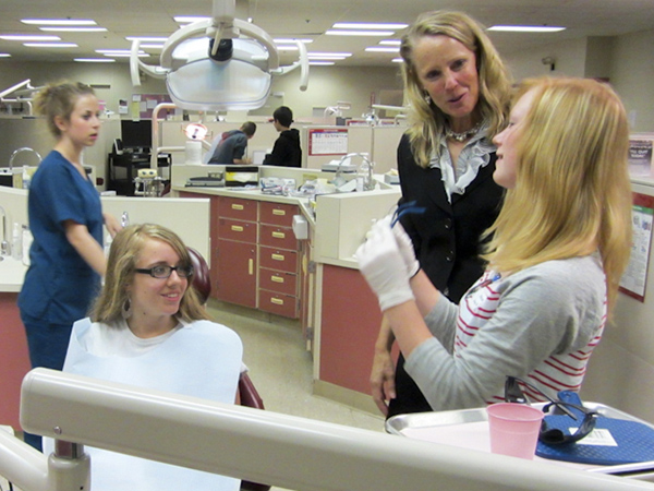 Rhonda J. Seebold, part-time instructor of dental hygiene, talks with middle-schoolers as they prepare to practice the skills of a dental hygienist.