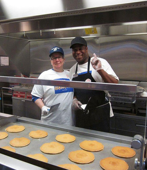 Dining Services worker Lee R. Whittington Sr. works the griddle with President Davie Jane Gilmour.