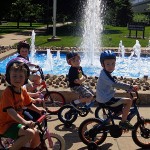 Biker buddies ride past a refreshing campus fountain.