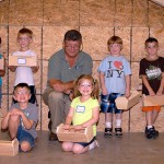 Gathering around their mentor, members of the class proudly display their woodworking success.