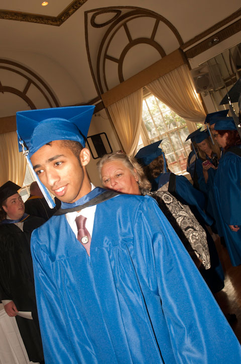 The Registrar’s Office’s Gail A. Ritchey helps a candidate adjust his hood.