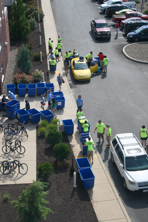 A welcome mat of blue bins and yellow T-shirts awaits families checking in at Dauphin Hall. 