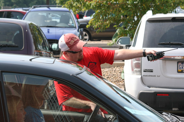 Walkie-talkie in hand, Matthew Helf, coordinator of residence life at Dauphin Hall, points a parent toward the unloading line.