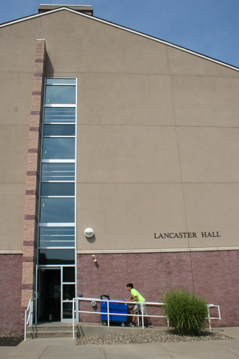A volunteer pushes a bin alongside Lancaster Hall.