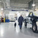 Al Thomas and his service dog, Jesse, walk side-by-side through the college's collision-repair facilities.
