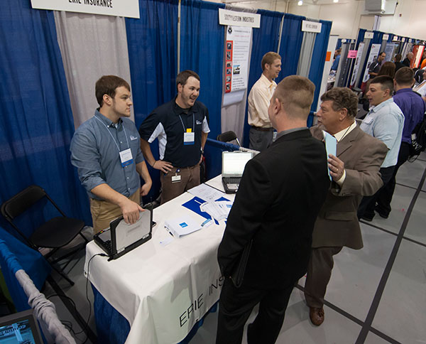 Erie Insurance's Corey A. Shank (left) and Cole S. Myers – both 2011 construction management alumni – greet visitors to their booth, including Marc C. Bridgens, dean of construction and design technologies (in right foreground).
