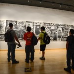 Students view a large-scale woodcut work by Kinney, who uses hidden pictures, symbols and patterns to weave imagery into narrative.
