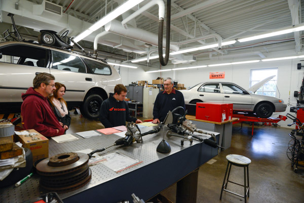 John J. Macko, assistant professor of automotive, assists a family in the Parkes Automotive Technology Center.