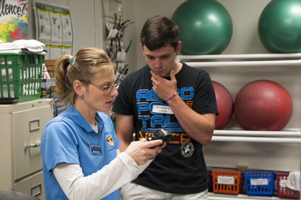 Erin J. McMurray, lab supervisor for the Physical Fitness Specialist Program, helps a Bloomsburg Area High School student with an electronic body fat analyzer.