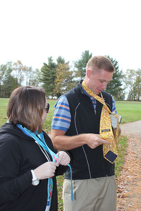 Valerie L. Fessler, director of alumni relations/annual giving, coaches Casey A. Poeth through some necktie 