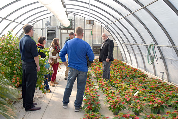 Standing amid rows of poinsettias in an ESC greenhouse, Dennis P. Skinner, an assistant professor of horticulture, talks about students' hands-on 