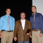 Presented with a plaque at the close of his lecture, Ryan P. Good is joined on stage by student nominators David J. Munn (left) and Jarad J. Askren.