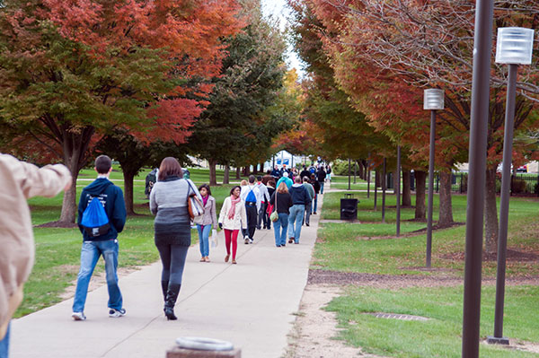 A crowd of pedestrians moves crisply down the campus mall.