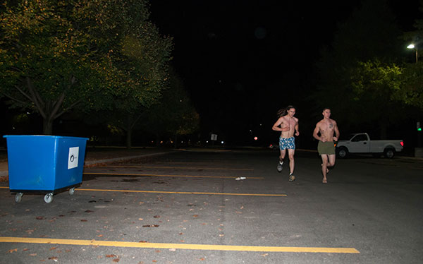 Nearly Naked Milers pass by a collection bin for clothing.