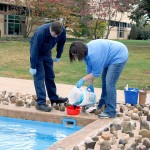 Allison A. Bressler, assistant director for student activities for programming and Greek life, pours blue dye into a funnel, under the supervision of Gary T. Pandolfi, a General Services refrigeration, heating and plumbing mechanic.