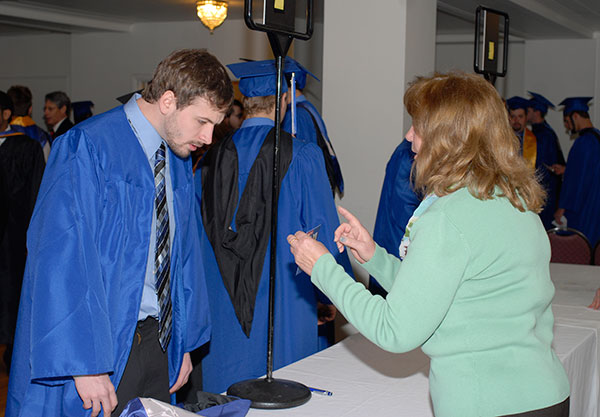 Paula M. Fisher, graduation assistant in the Registrar's Office, helps a soon-to-be graduate during her final commencement check-in before retirement.