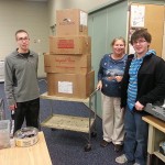 Mail processing clerk Judy L. Phillips accepts items from Gaven D. Crosby (left) and Eric T. McMahon for holiday shipment to troops abroad.