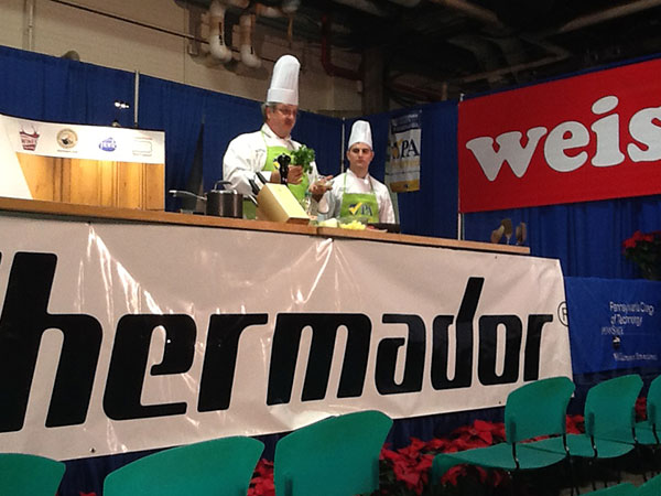 Samuel J. Stammer, of Ithaca, N.Y., a culinary arts technology major (right), joins Chef Paul E. Mach, assistant professor of hospitality management/culinary arts, on stage. The students and Chef Paul, assisted by Chef Michael J. Ditchfield, instructor of hospitality management/culinary arts, prepared a wide variety of dishes – Mushroom Cappuccino, La Bonne Vie Camembert and Shrimp Alfredo over Fettuccine, Thai Coriander Beef, Quinoa Ratatouille Salad, and Sweet Potato/Sweet Corn/Horseradish Ice Cream, among them – over a busy three days.