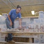 Nicole Reyes-Molina scoops mortar for a 16-foot by 16-foot wall in the Construction Masonry Building.