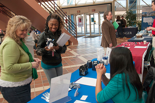 Alumna Joni Bilbay (in green scarf) and Maria Cockerham (seated), both of HCR ManorCare, talk with a student.
