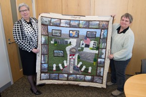 Christine E. Atkins delivers her Centennial quilt to President Davie Jane Gilmour, who assists in its display.