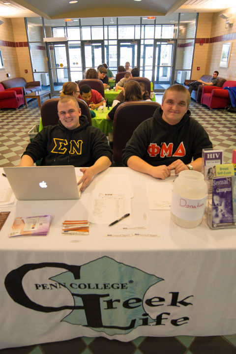 Staffing the check-in table are Sigma Nu's Christopher M. Scheller (left), who majors in building science and sustainable design: architectural technology concentration, and Phi Mu Delta's Alexander R. Wetzel, an industrial and human factors design student.