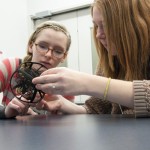 Girls inspect the intricacies of an object made in the college’s additive manufacturing lab.