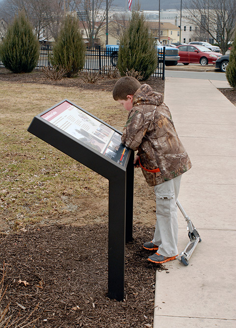 A young campus visitor pauses along the college's informative History Trail to learn more about the Remembrance Garden.