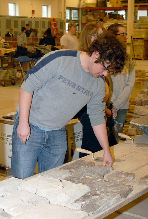 In a literal dry run, a Penn State student finalizes a mortarless assembly of artificial stone before it is affixed to a nearby wall.