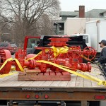 Barely a week from field service, a newly sandblasted and painted wellhead arrives at the Center for Business & Workforce Development. Among those on hand for the special delivery are (at right) General Services custodian Jeff G. Rotoli; Daniel R. Mendell, ShaleNET U.S. consultant/instructor; and (in checkered shirt) John F. Strittmatter, director of the ShaleNET U.S. regional hub.