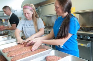 Students Cassandra B. Mohr, left, and her roommate Paige E. Monk, handle pans of meatloaf.