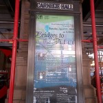 The orchestra's role in the "Bridges to the Future" concert is noted on a poster outside.