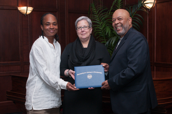 The family of the late Theresa Jackson accepts a posthumous degree from the college president.