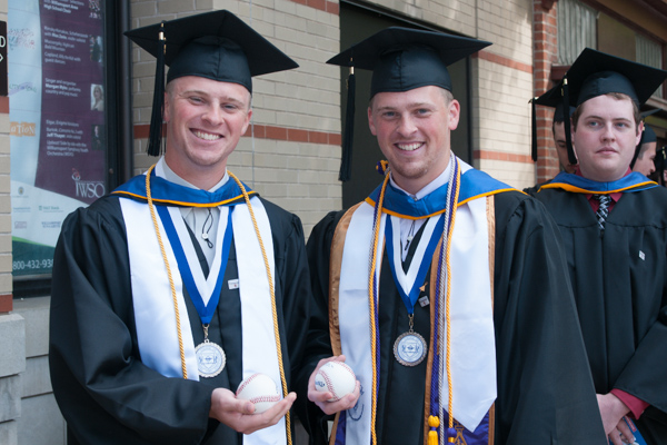 Wildcat baseball team members Cody E. Buterbaugh, left, and his twin brother, Zachary J., carry baseballs into the commencement to be signed by the college president (who also chairs the Little League International Board of Directors). 